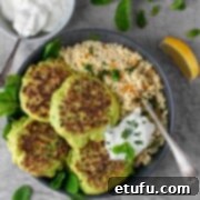 Four pea fritters in a bowl with a portion of couscous and a dollop of Greek yoghurt, ready to be served.