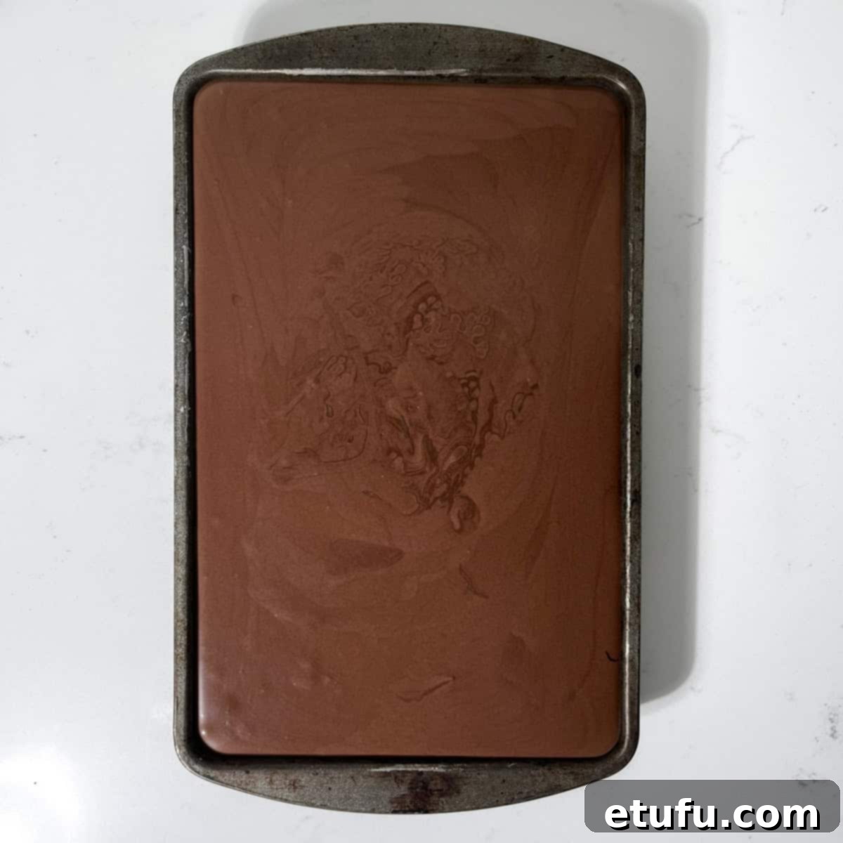 Dark chocolate ice cream mixture poured into a baking tray, ready to be frozen.