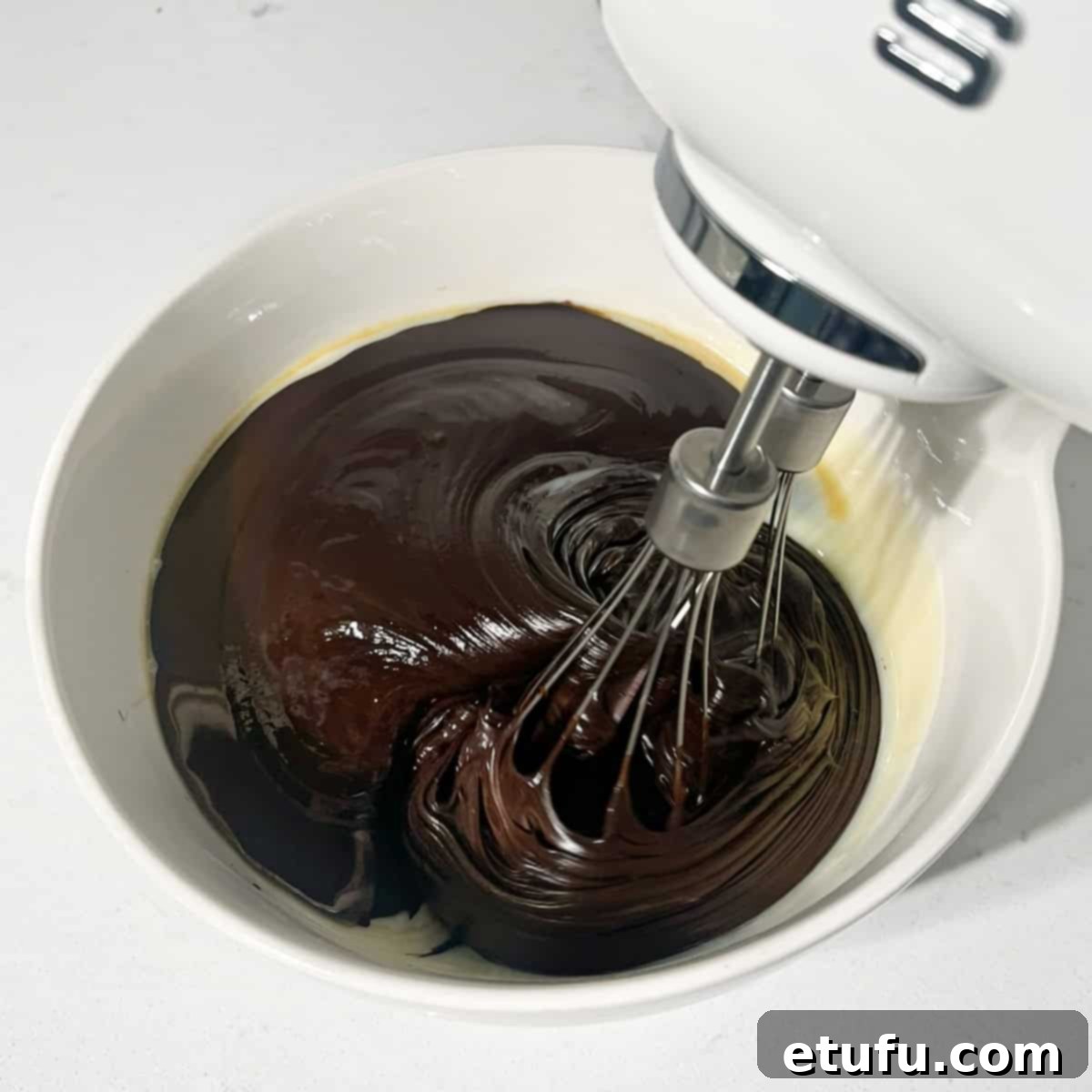 Whisking melted chocolate and condensed milk together in a bowl.