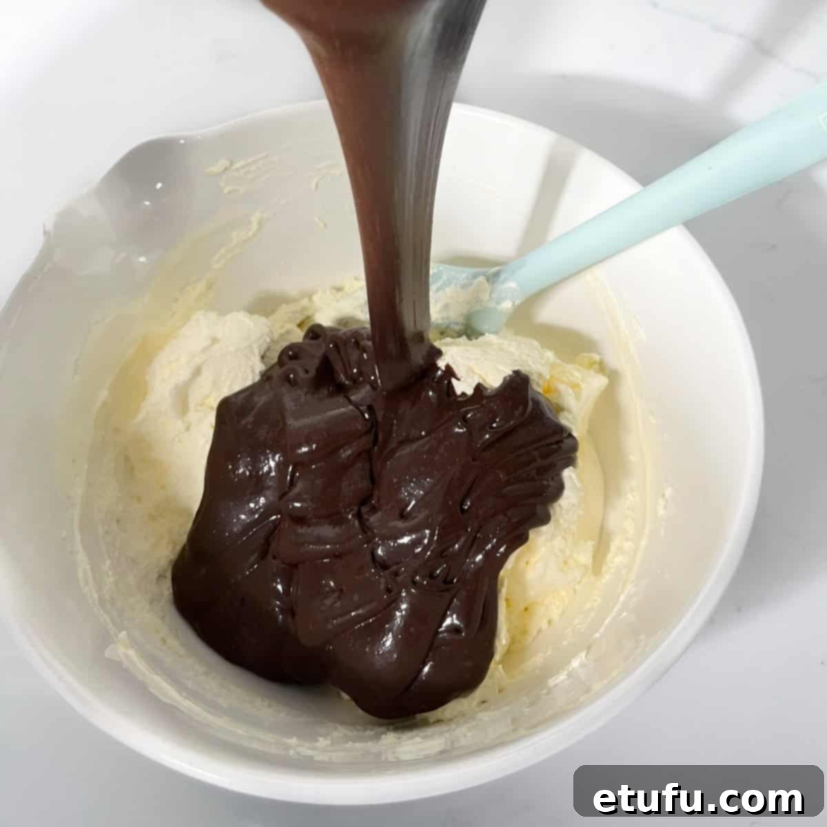 Adding half of the rich chocolate mixture to the fluffy whipped cream.