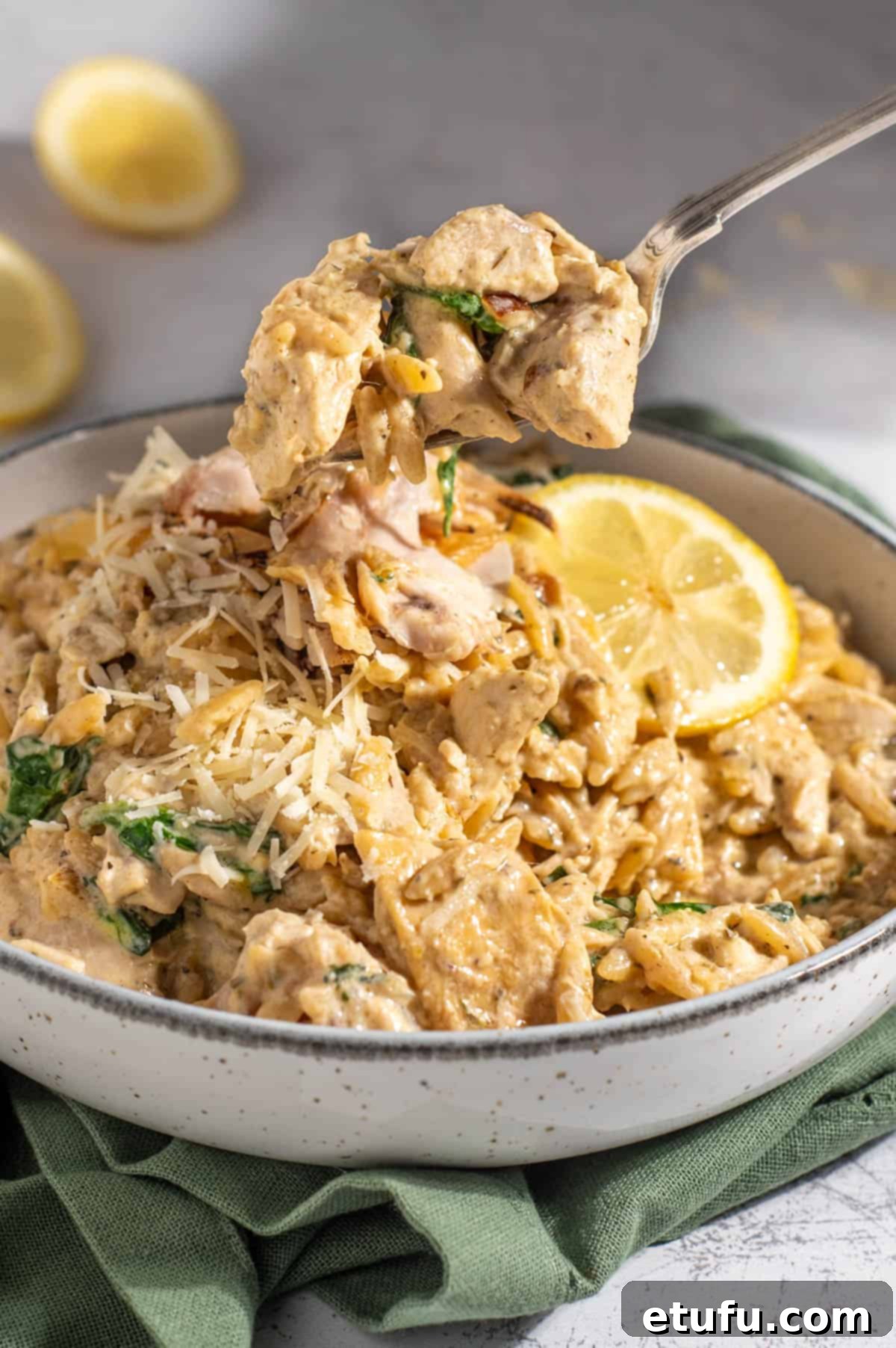 Lemon chicken orzo pasta with a spoonful on a fork, highlighting its creamy texture.