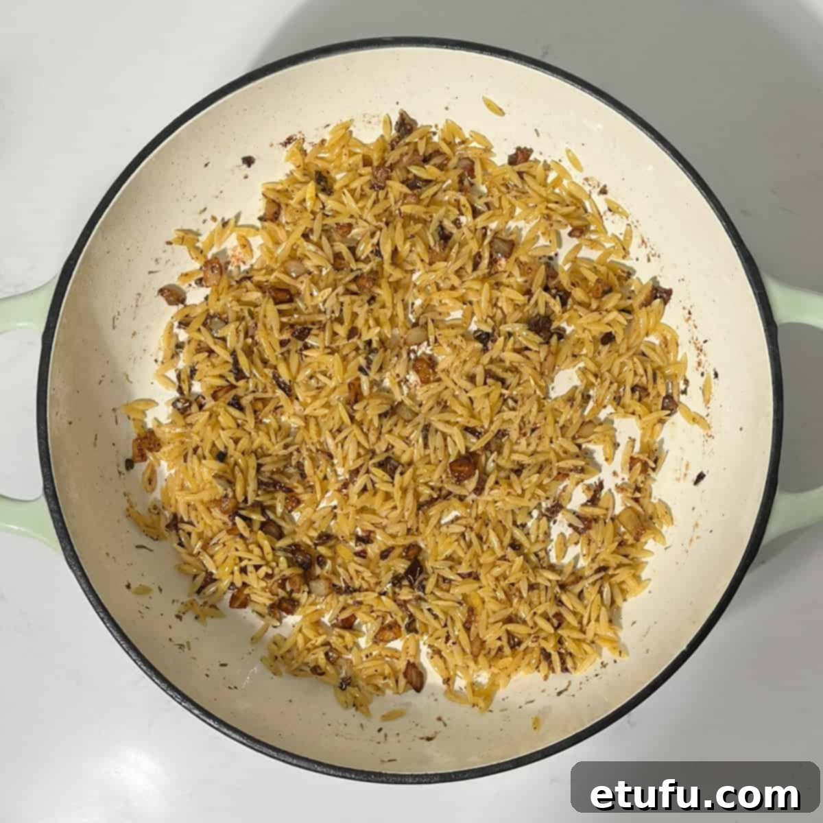 Toasting orzo with onions for the lemon chicken orzo pasta in the pan.