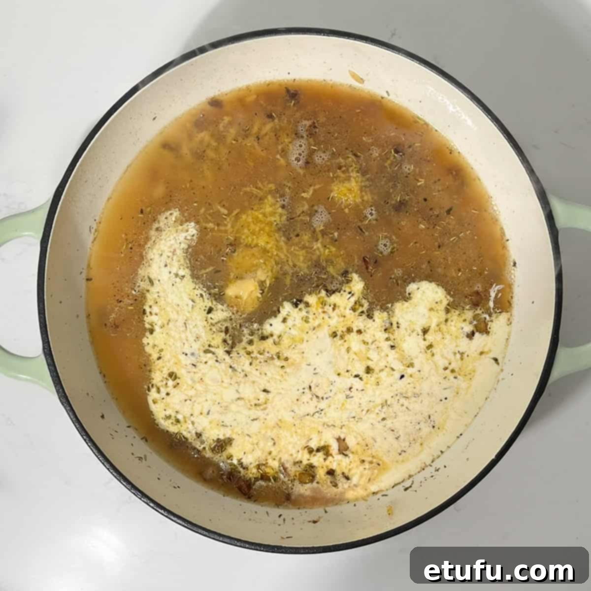 Adding chicken stock and cream to the toasted orzo in the pan.