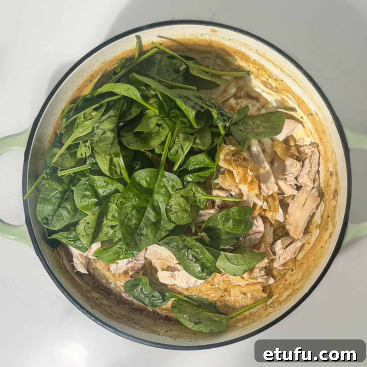 Adding spinach and parmesan to the lemon chicken orzo pasta in a large saucepan.