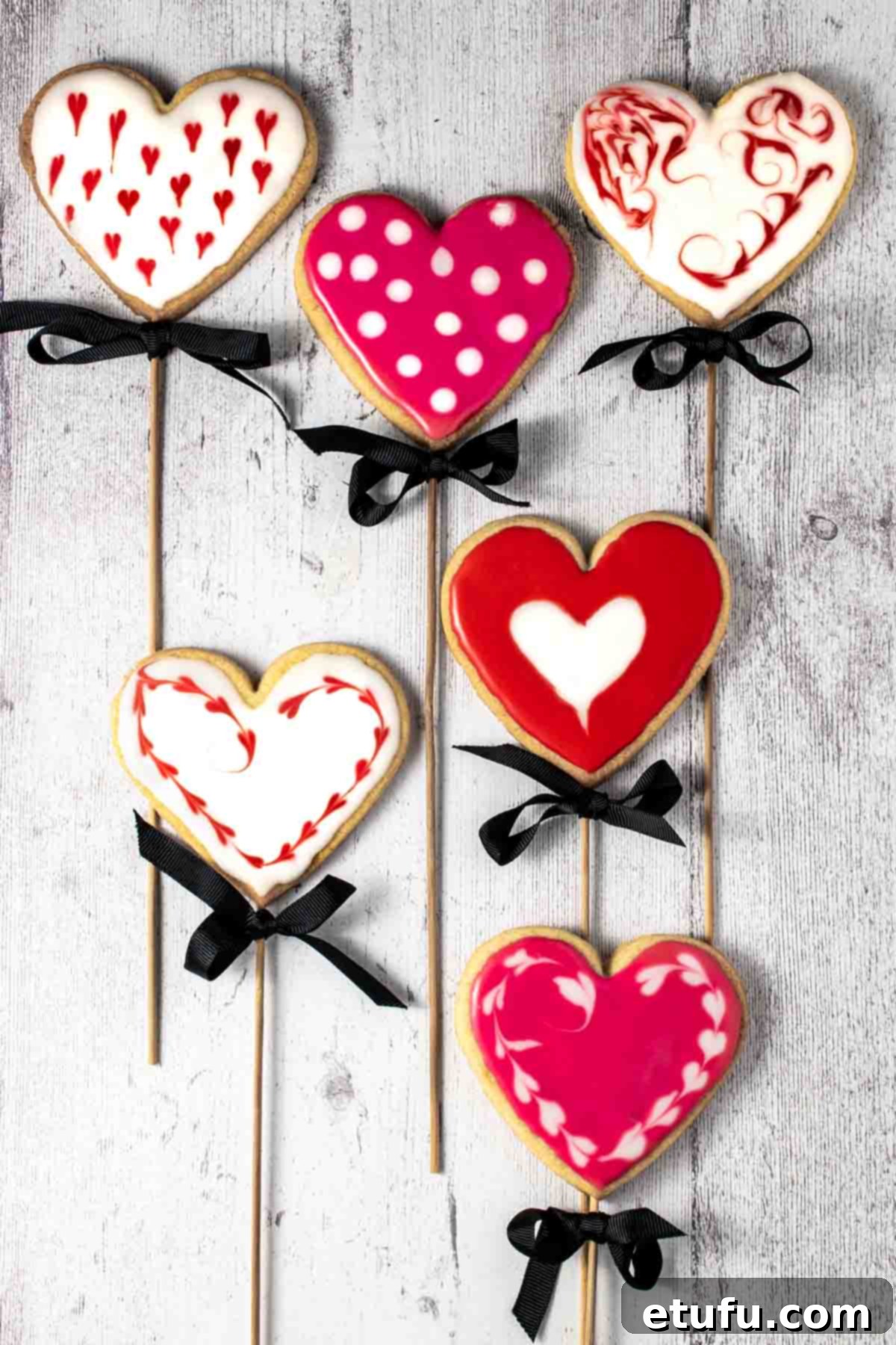 Six valentine's biscuits on sticks, beautifully decorated and arranged.