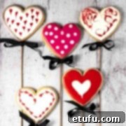 Five valentine's sugar biscuits on sticks, artfully decorated.