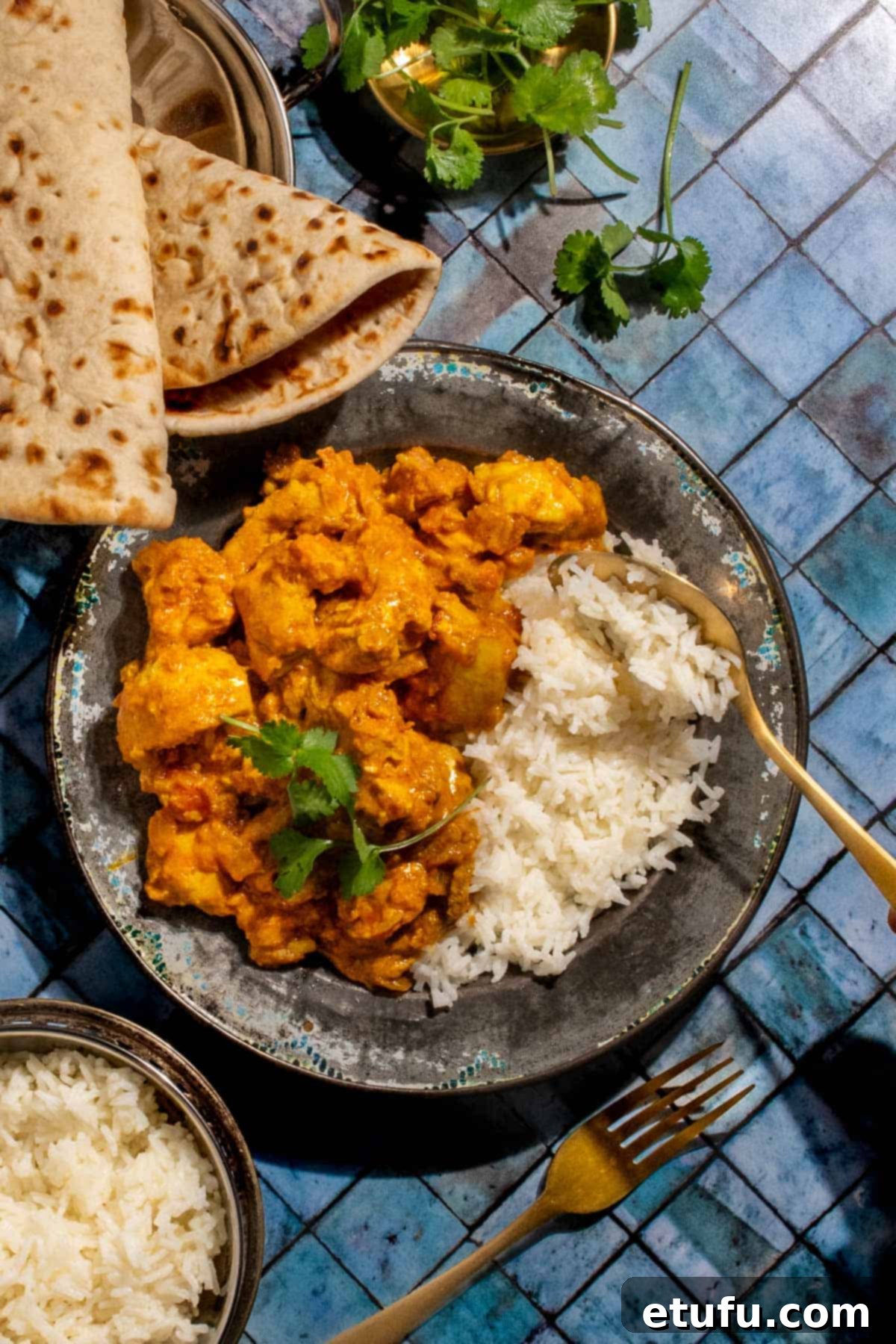 Chicken karahi curry in on a plate with rice on a blue background. 