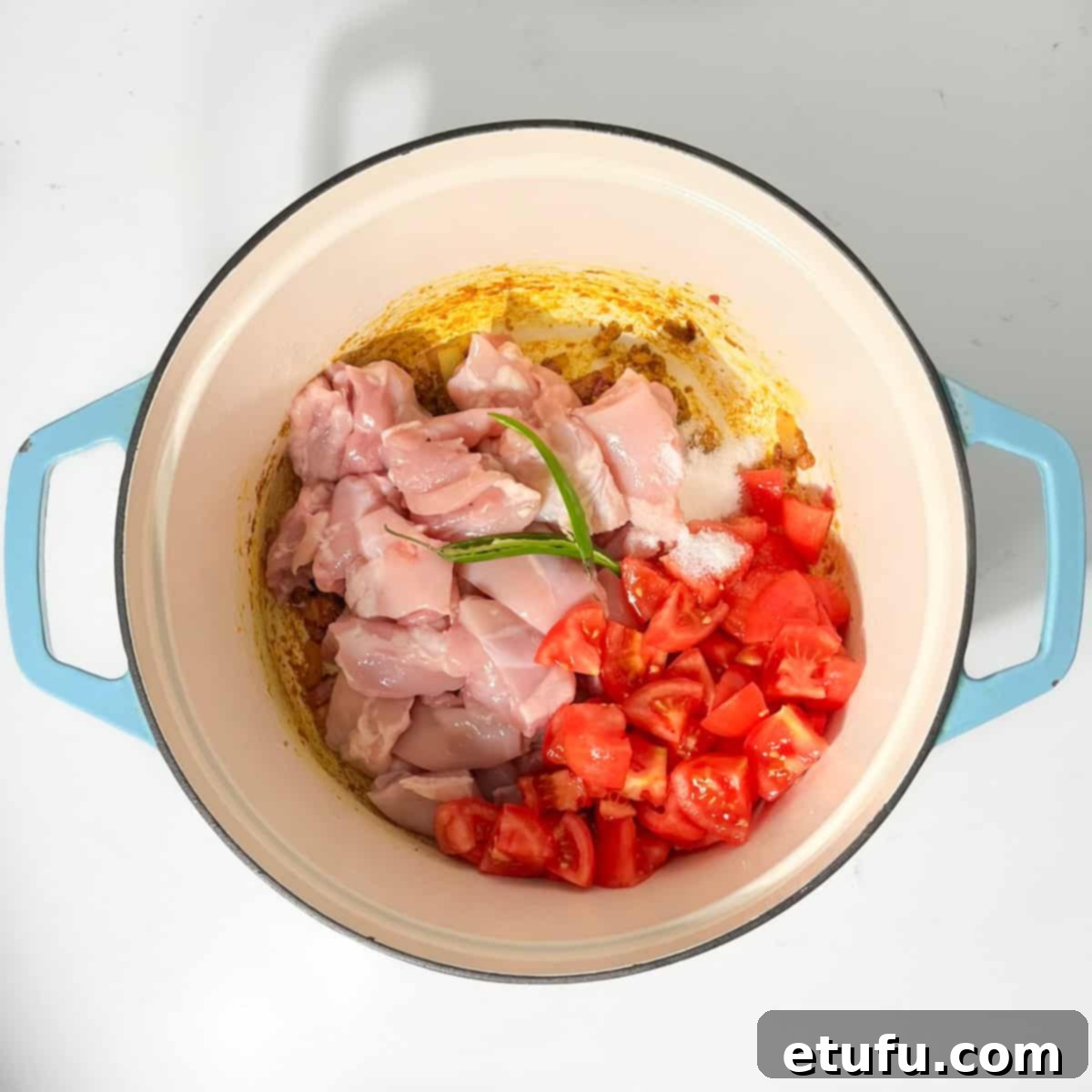 Adding the chicken and chopped tomatoes to the saucepan for the chicken karahi curry.