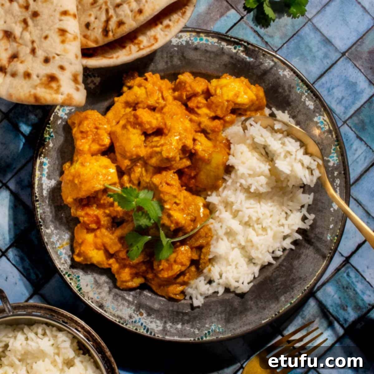 Chicken karahi curry in on a plate with rice on a blue background.
