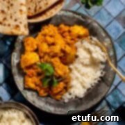 Chicken karahi curry in on a plate with rice on a blue background.