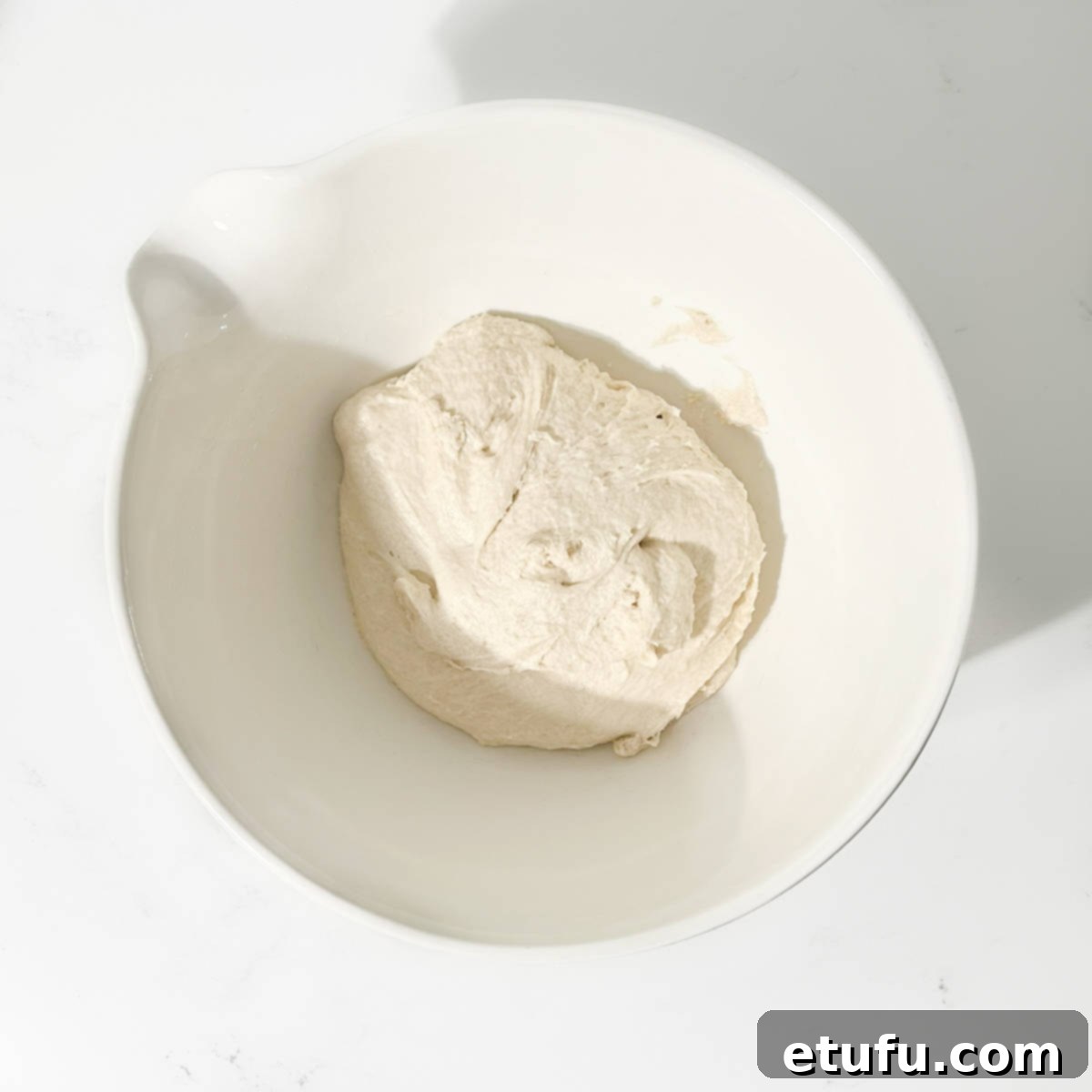 Transferring the soft naan dough into a lightly oiled bowl for rising.