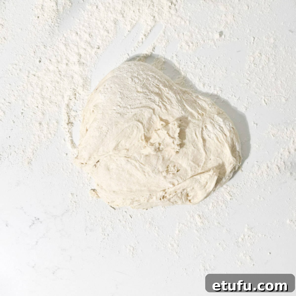 Turning the risen naan dough out onto a generously floured surface.