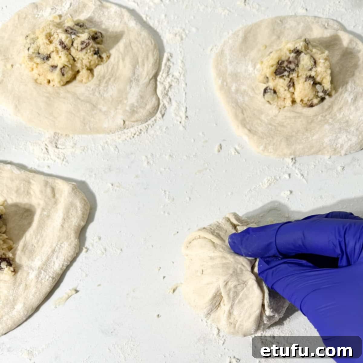 A hand pinching the edges of the dough together over the filling, creating a sealed parcel.
