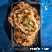 A pile of Peshwari naans in a baking dish on a blue background.