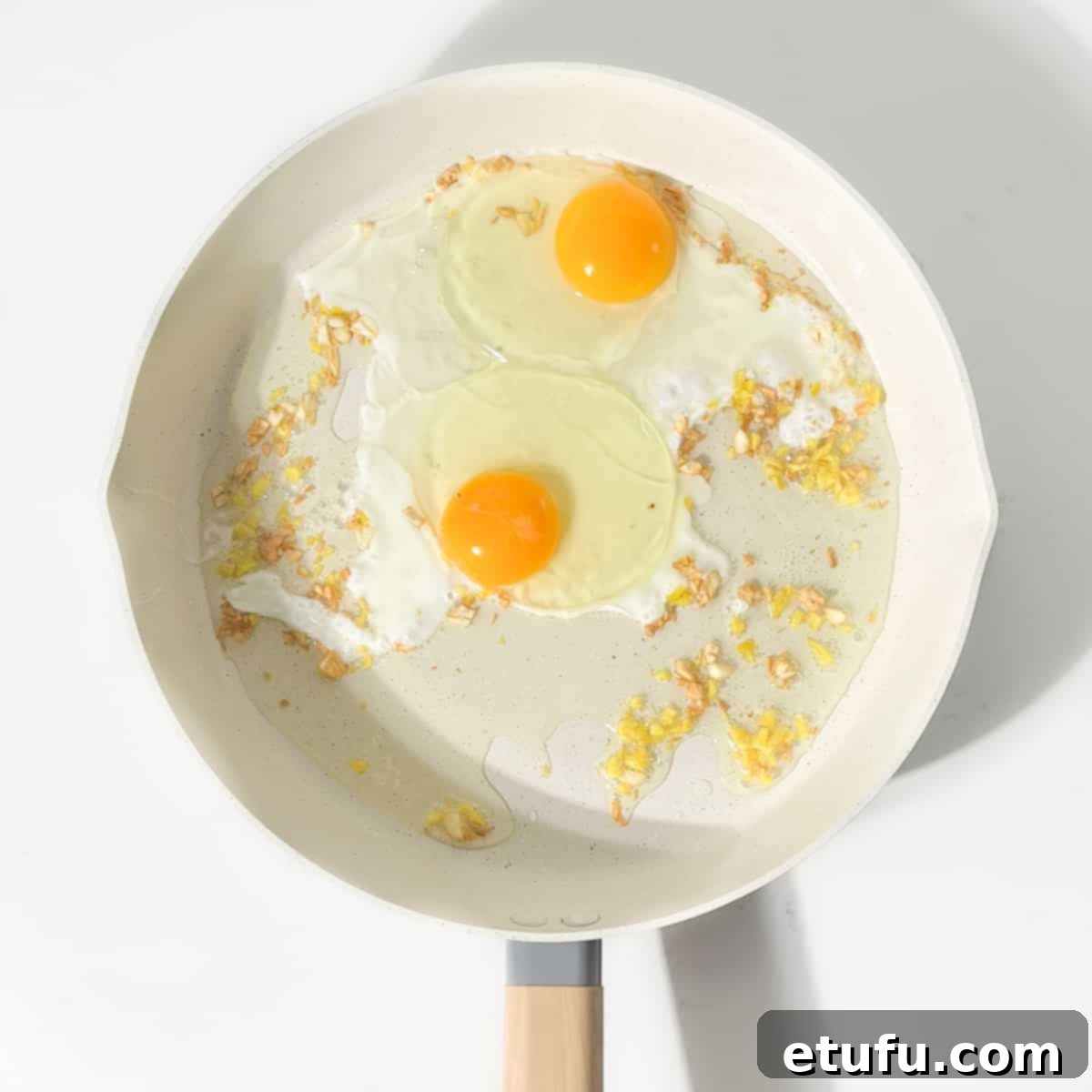 Breaking the eggs into the pan with the garlic and ginger.