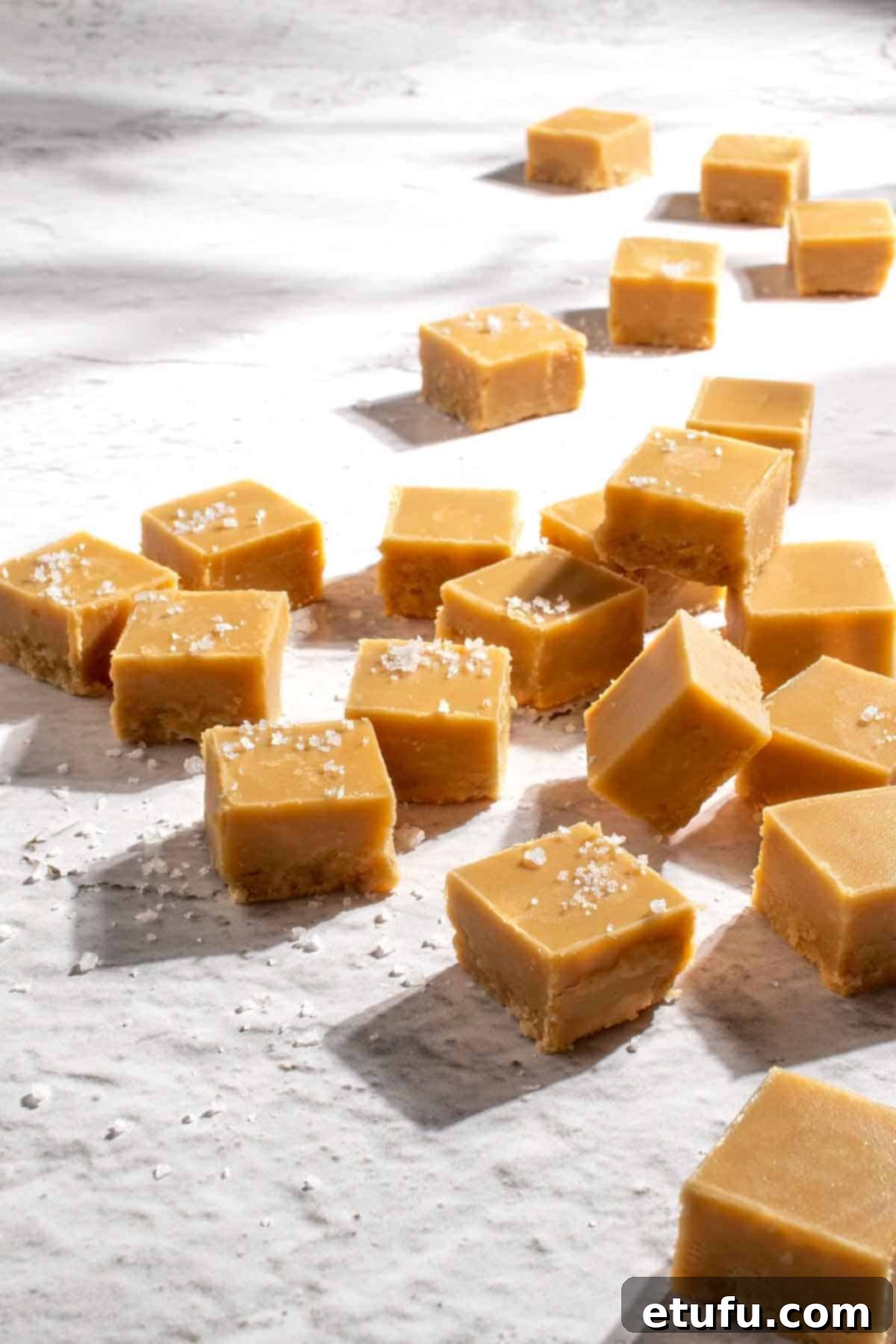 Microwave peanut butter fudge scattered across a rough, white surface.