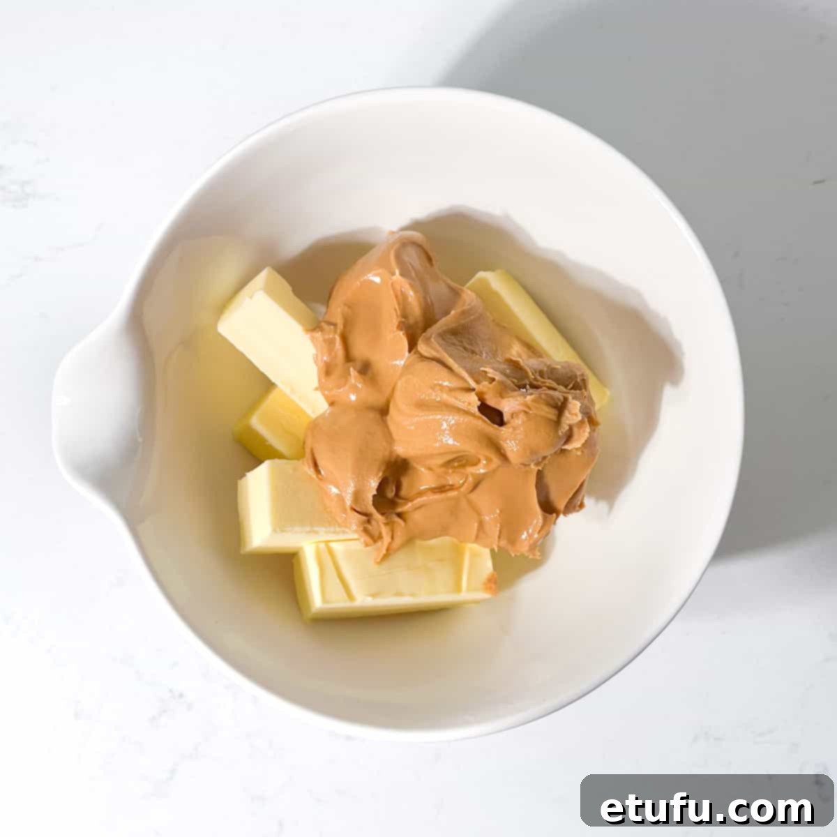 Adding the butter and peanut butter to a white bowl for the microwave peanut butter fudge.