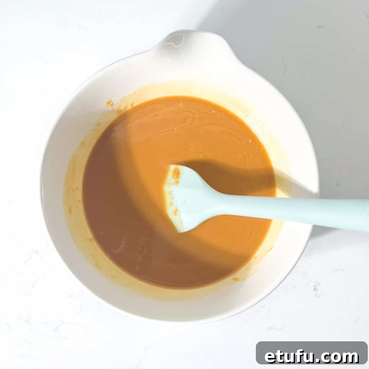 Melted peanut butter and butter in a white bowl.