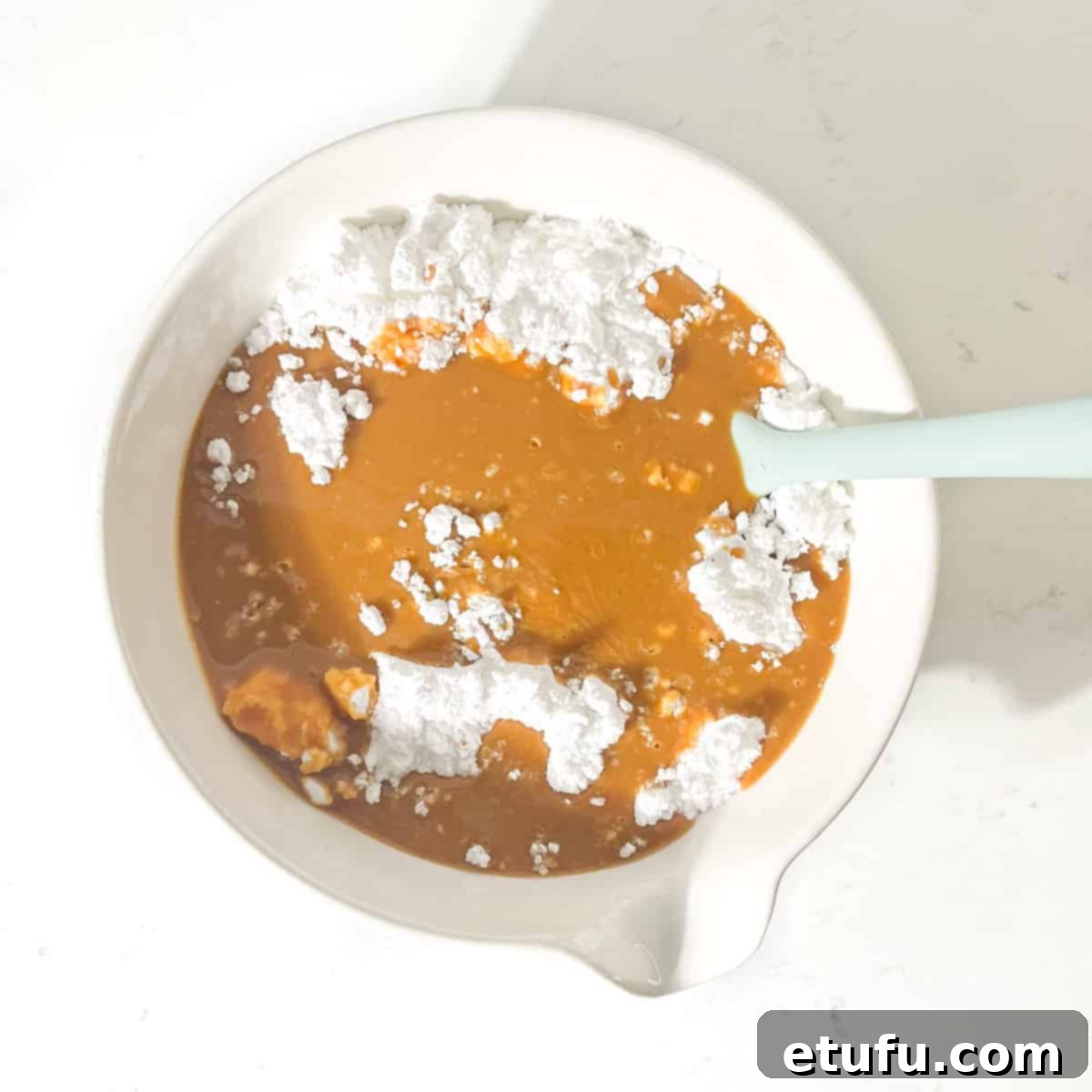 Adding the melted peanut butter and fudge to the icing sugar.