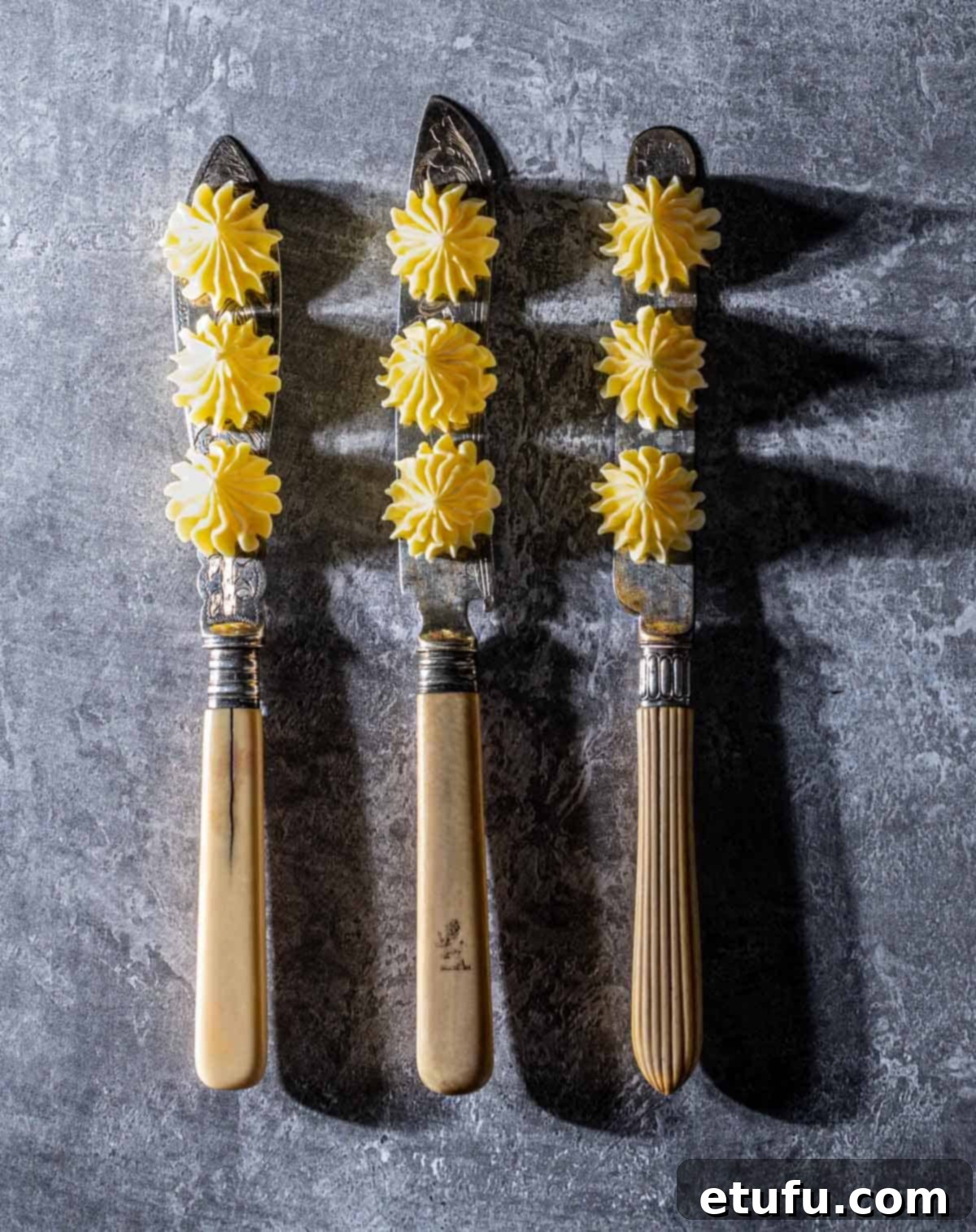 Elegant butter rosettes piped onto vintage knife blades, ready for serving.