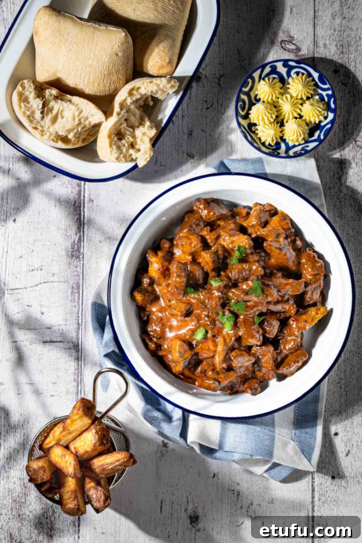Trinchado in a white bowl with a dish of bread rolls and a small basket of chips.