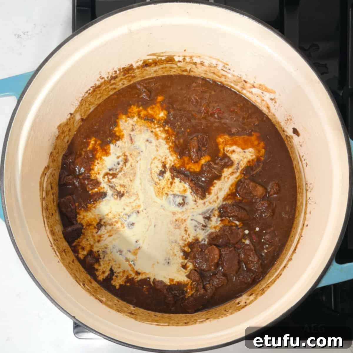 Adding cream to the Trinchado in a large pot.