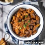 Trinchado in a white bowl with a dish of bread rolls and a small basket of chips.