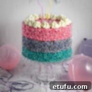 A three layered Rice Krispie cake on a cake stand, surrounded by balloons.