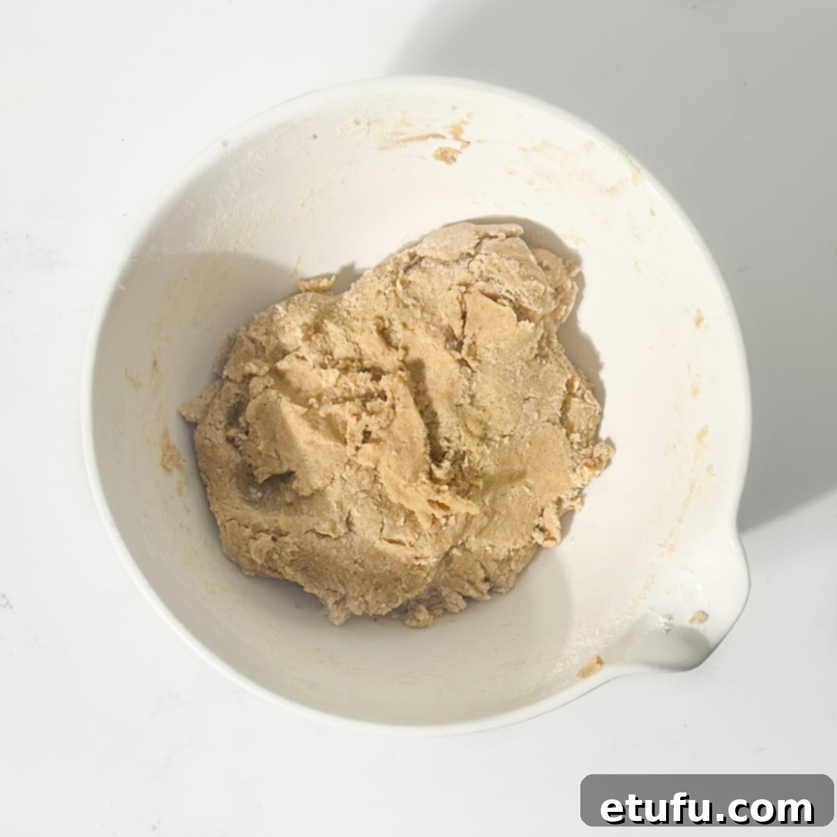 Soetkoekies mixture brought together by hand in a large white bowl.