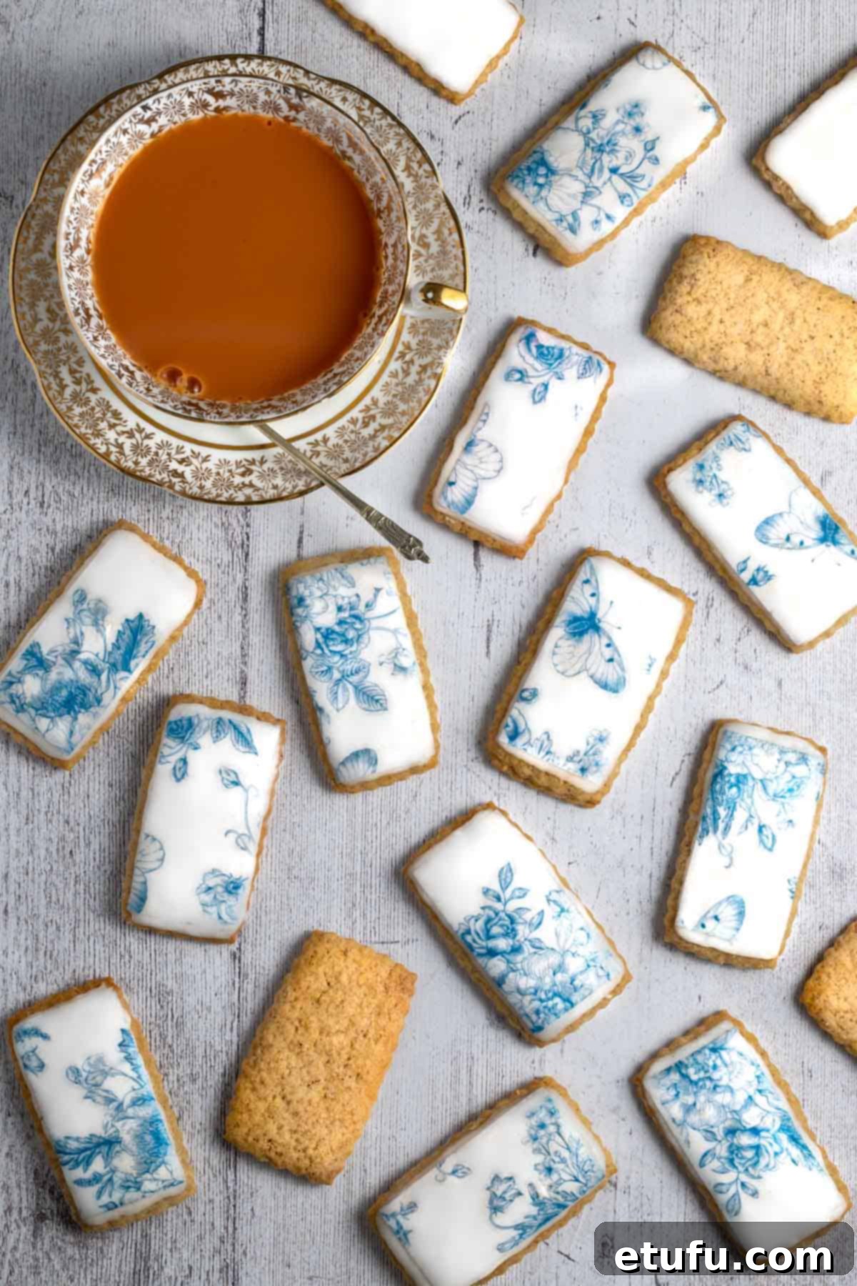 Spice biscuits, or soetkoekies, scattered across a white table with a cup of tea on the side.