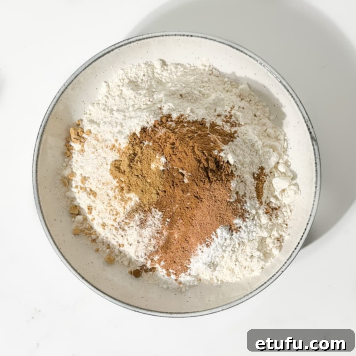 Adding spices to dry ingredients for spice biscuits.