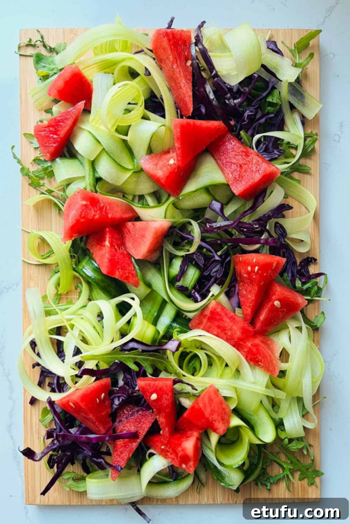 Rainbow salad base with rocket, red cabbage, celery and cucumber ribbons, now including watermelon triangles.