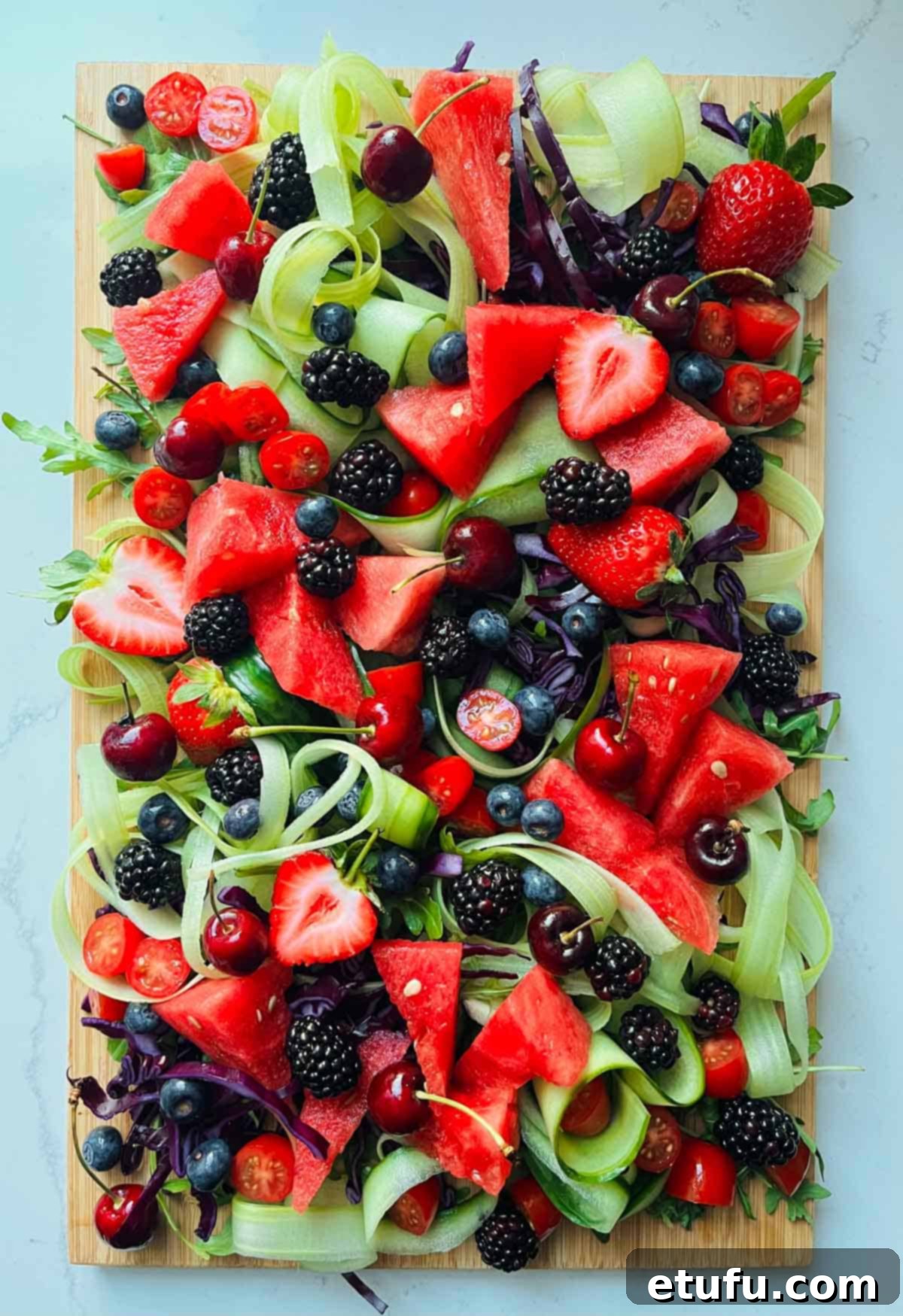 Rainbow salad with all previous ingredients, now including bright red cherries with stalks.