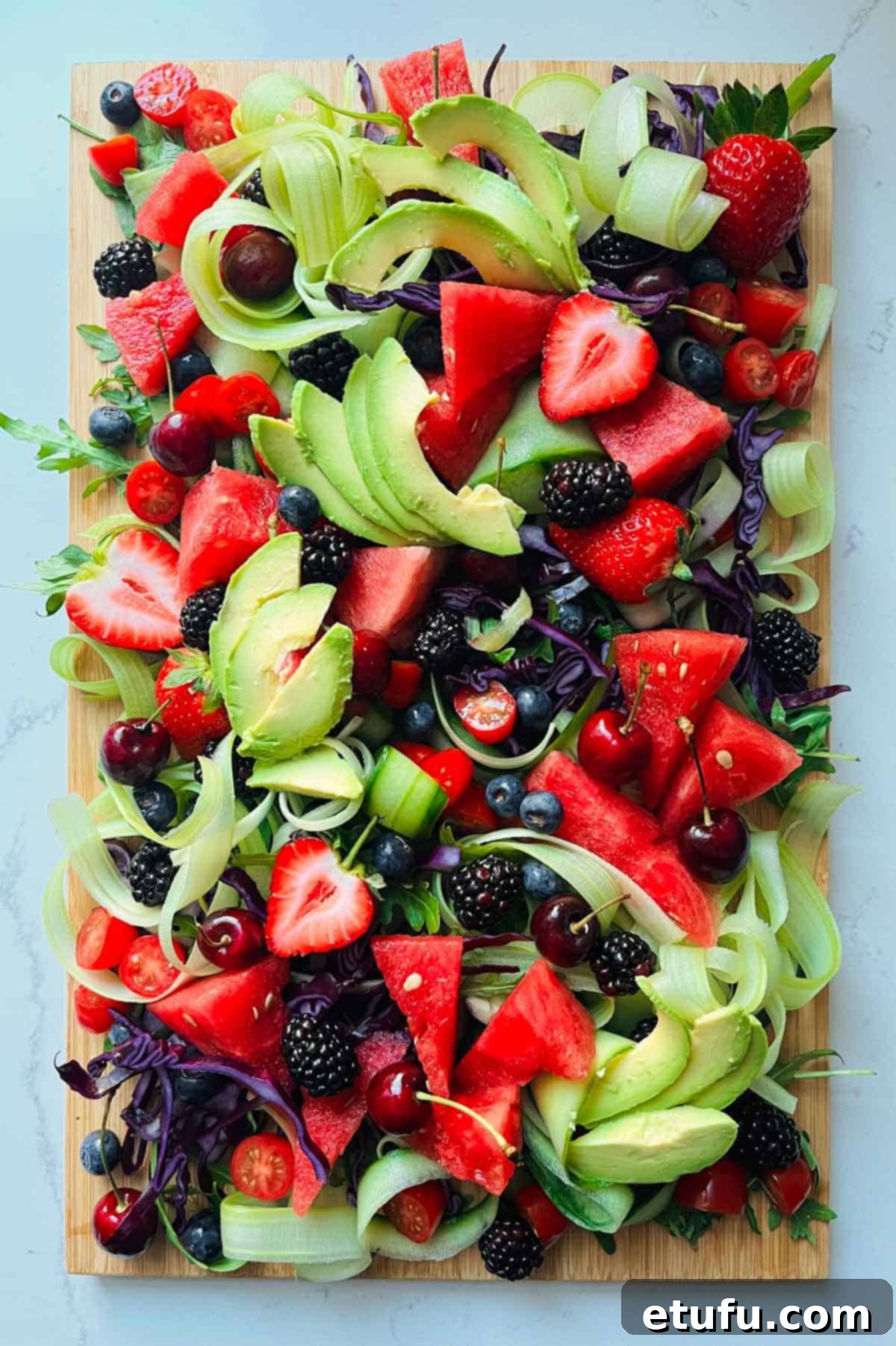 Rainbow salad with all ingredients, including fanned slices of creamy avocado.