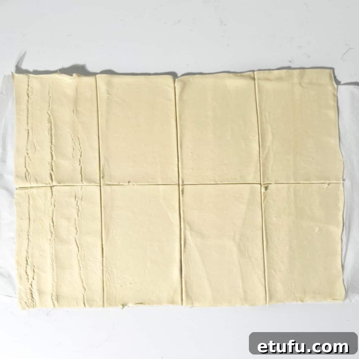 A sheet of puff pastry precisely cut into eight equal rectangles, ready for filling.