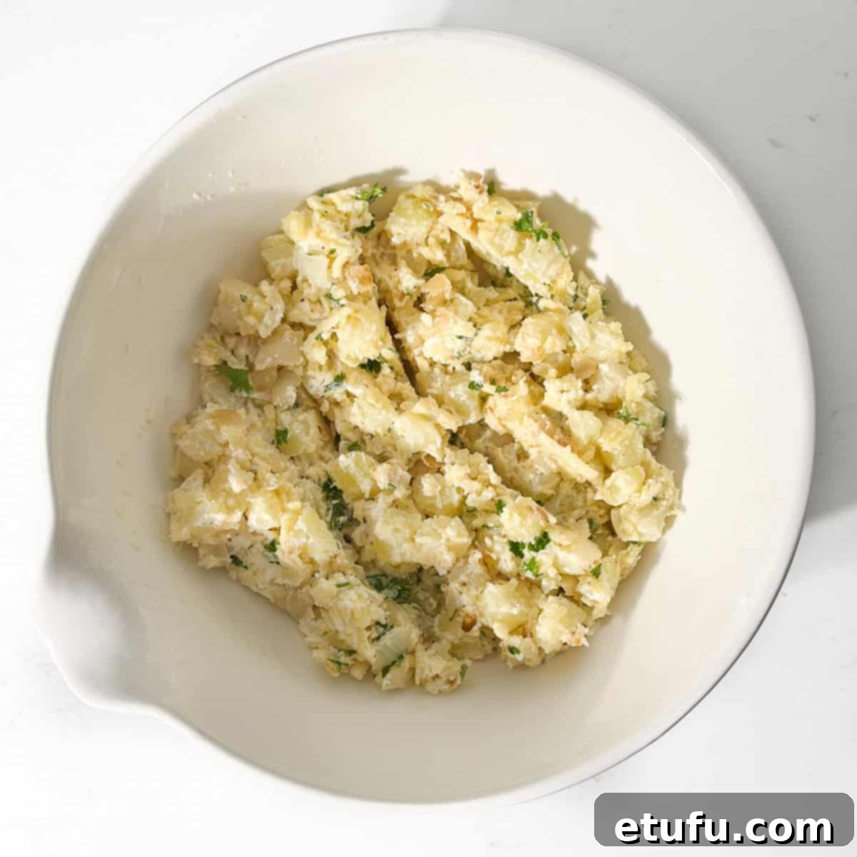 The complete cheese and onion pasty filling mixture in a large white mixing bowl, stirred and ready.