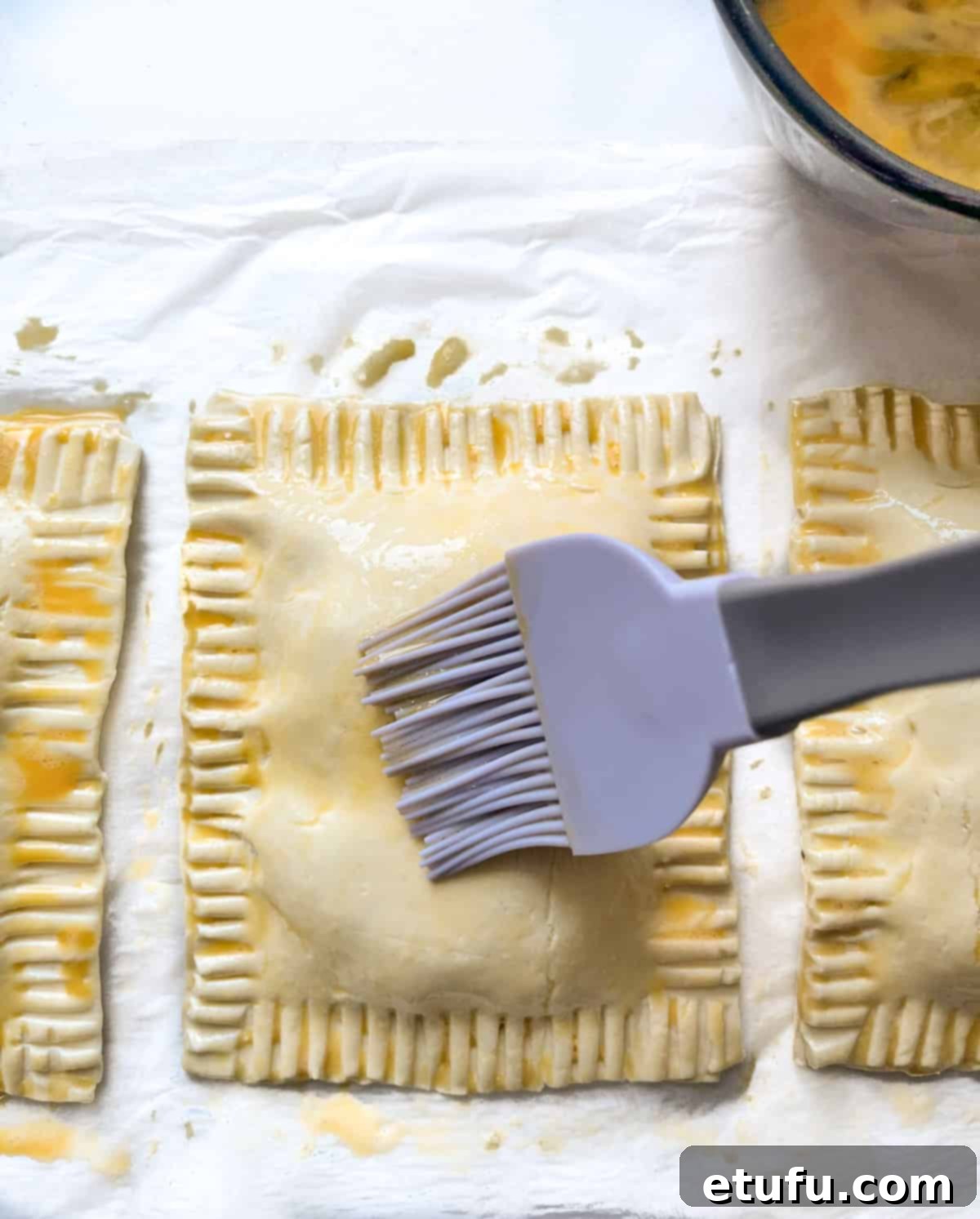 Four cheese and onion pasties on a baking tray, expertly brushed with egg wash for a golden finish.