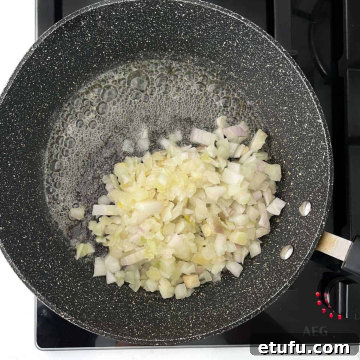 Finely chopped onions being added to a hot frying pan with melted butter for the pasty filling.