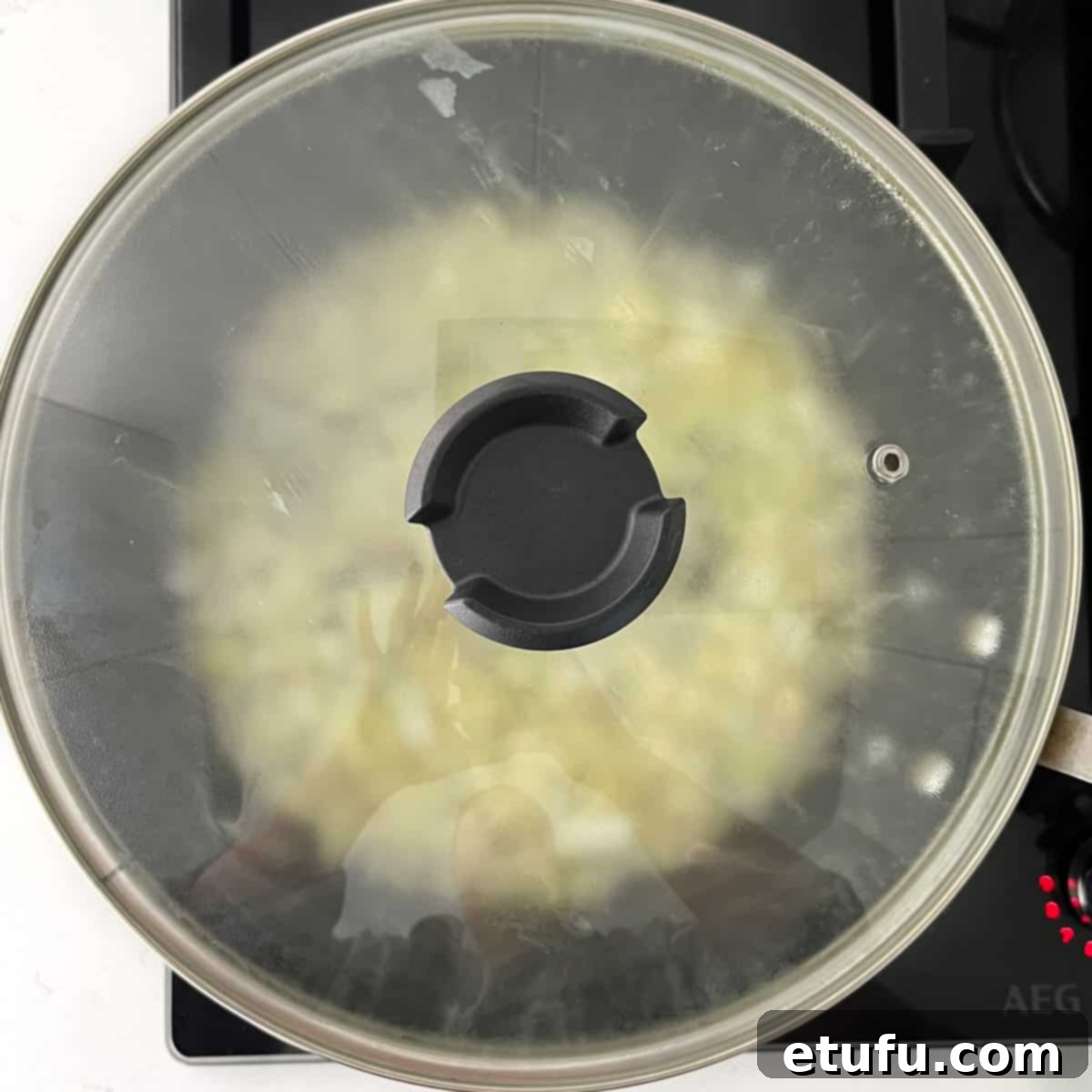 Onions gently frying in a covered large frying pan to caramelize and soften.