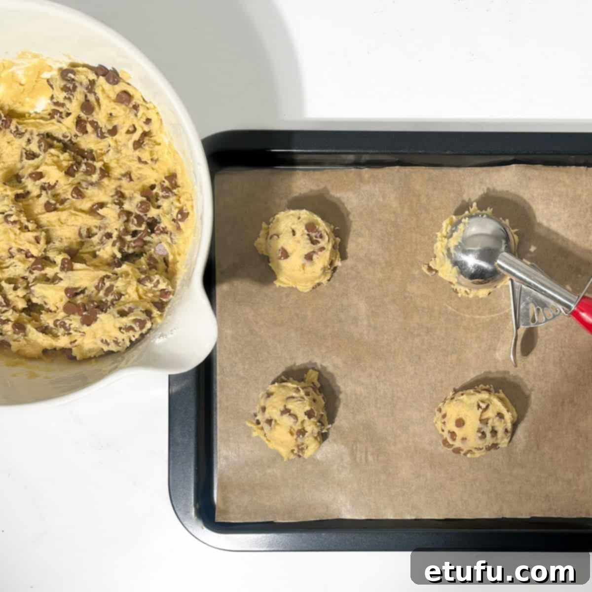 Scooping perfectly sized balls of chocolate chip cookie dough onto a baking sheet lined with parchment paper.