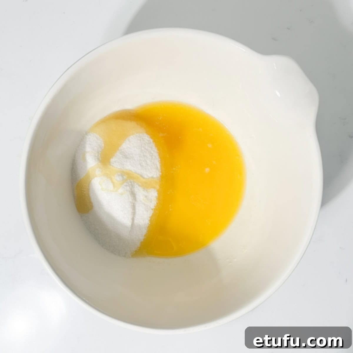 Melted butter, white sugar, and golden syrup being combined in a large white bowl.