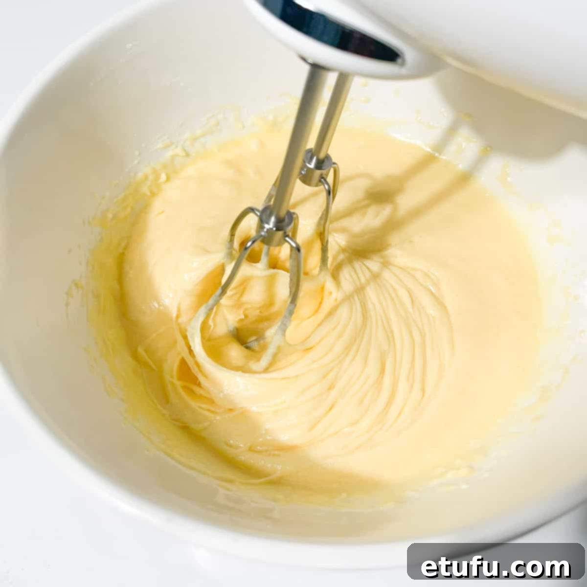Beating the mixture of eggs, butter, and sugar for chocolate chip cookies until light and fluffy.