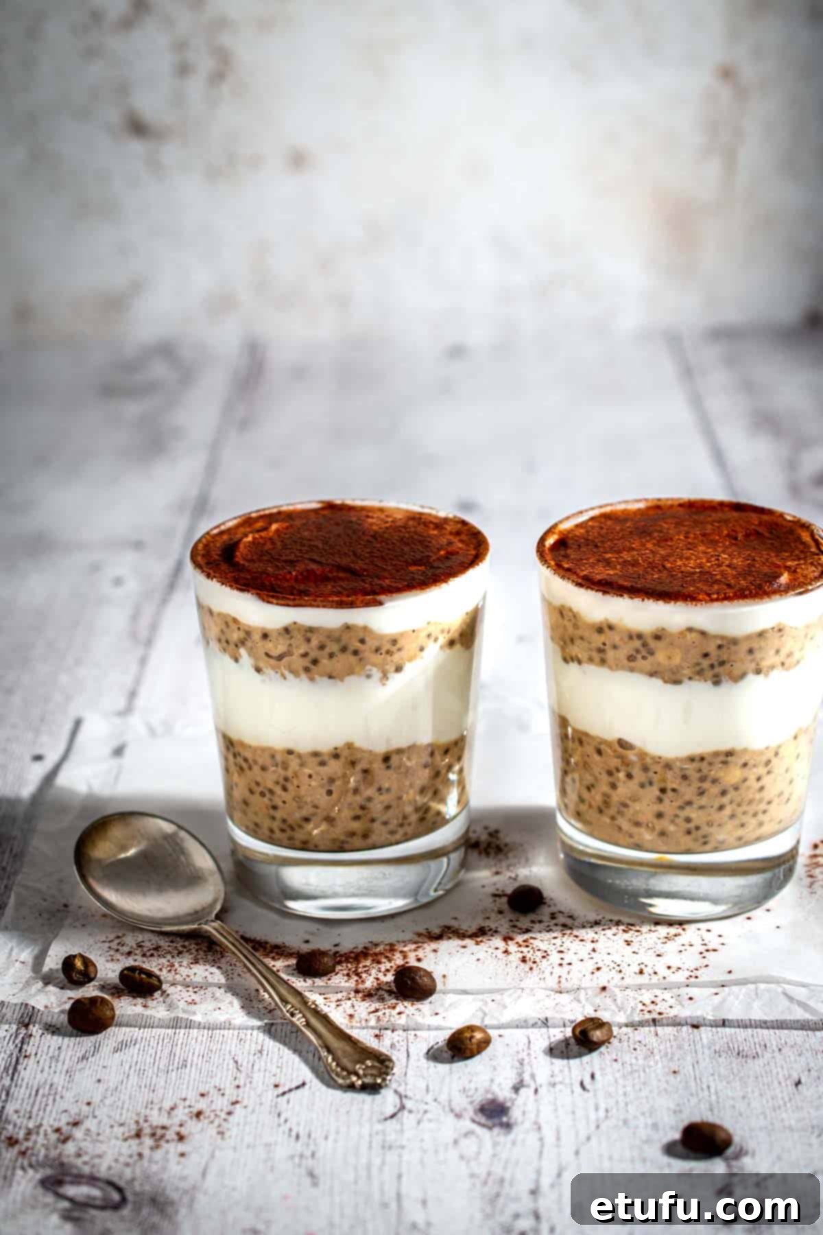 Two pots of prepared Tiramisu overnight oats, artfully layered with coffee-infused oats and creamy mascarpone-like topping, dusted with cocoa powder.
