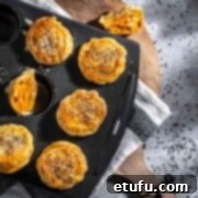 Butter chicken pies in a muffin pan on top of a wooden chopping board.