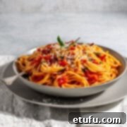 Spaghetti arrabiata in a grey bowl on a white napkin, ready to be served.
