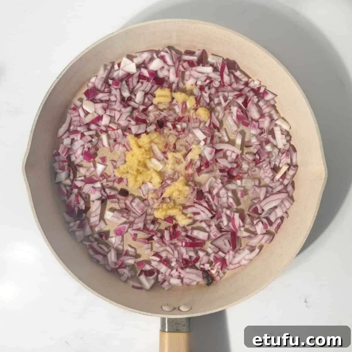 Chopped onions and garlic sizzling gently in olive oil in a large frying pan.