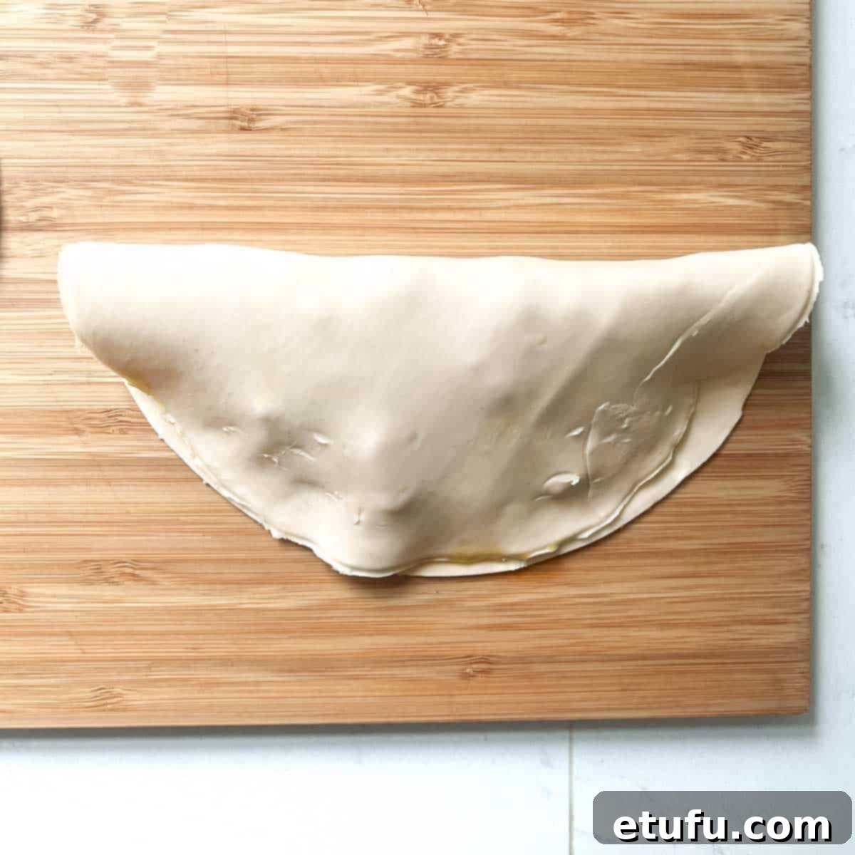 Golden Flaky Creamy Chicken Leek Pies 15 A chicken and leek pie with the pastry folded over and edges joined, ready for crimping.