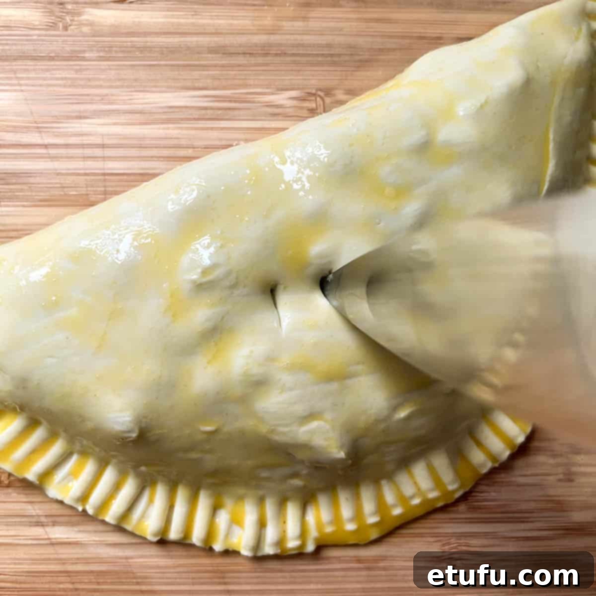 Golden Flaky Creamy Chicken Leek Pies 18 Two small holes being stabbed into the top of a chicken and leek pie with a knife tip.