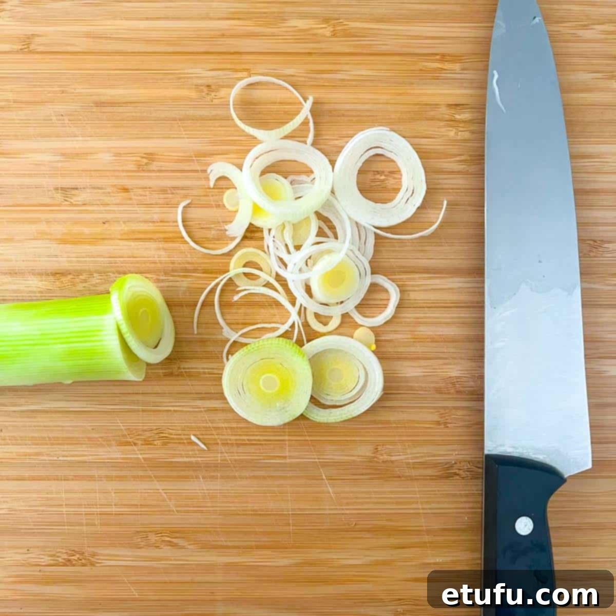 Golden Flaky Creamy Chicken Leek Pies 6 A wooden chopping board with neatly thinly sliced leeks, ready for cooking.