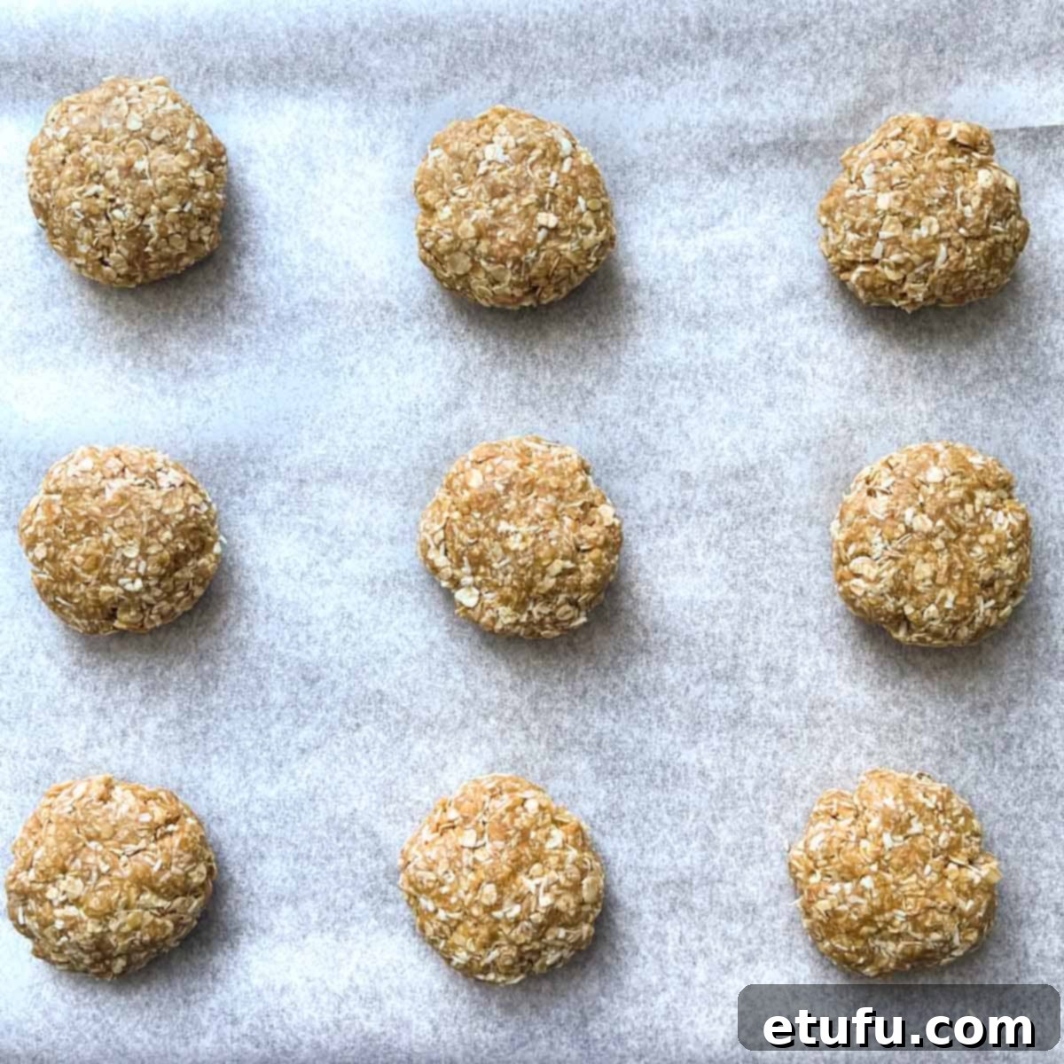 Coconut biscuit dough balls on a baking tray.